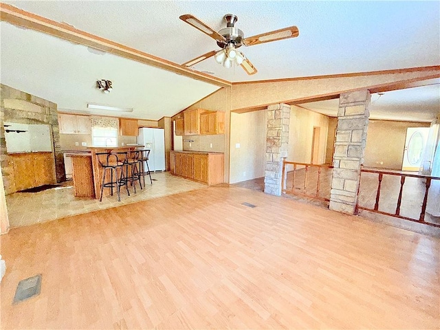 interior space featuring decorative columns, visible vents, light wood-style flooring, lofted ceiling with beams, and ceiling fan