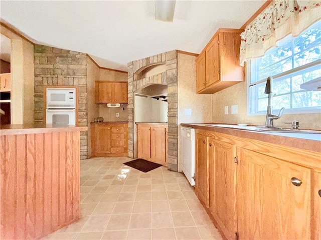 kitchen with lofted ceiling, white appliances, light tile patterned flooring, and a sink