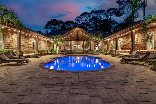 pool at dusk with a patio area