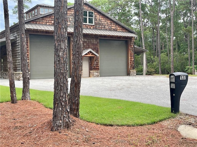 view of side of property featuring a garage, metal roof, aphalt driveway, and a standing seam roof