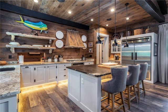 kitchen with extractor fan, wood walls, wood-type flooring, a center island, and white cabinets