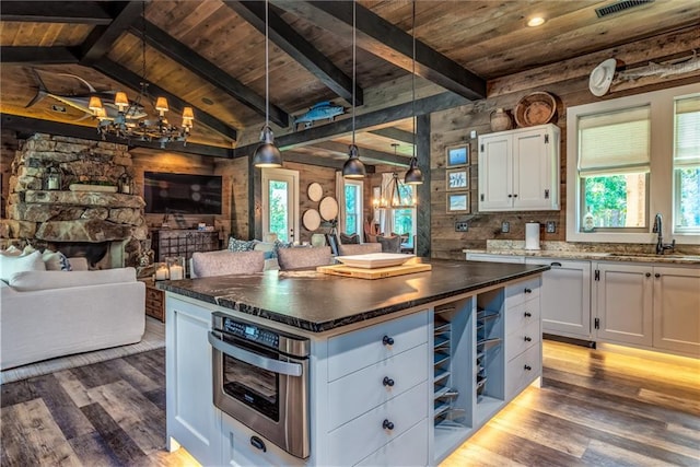 kitchen featuring open floor plan, white cabinets, a sink, and wooden ceiling