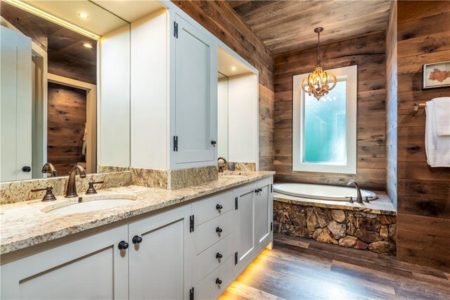 bathroom with vanity, wooden walls, and tiled bath