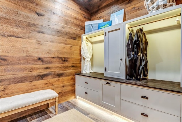 mudroom with light wood-type flooring and wood walls