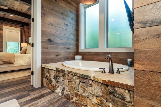 bathroom featuring hardwood / wood-style floors, a tub to relax in, and wooden walls