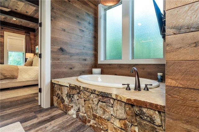 ensuite bathroom with ensuite bath, wooden walls, a bath, and wood finished floors