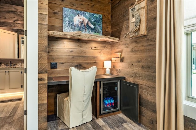 interior space featuring dark wood-type flooring, wine cooler, sink, and wooden walls