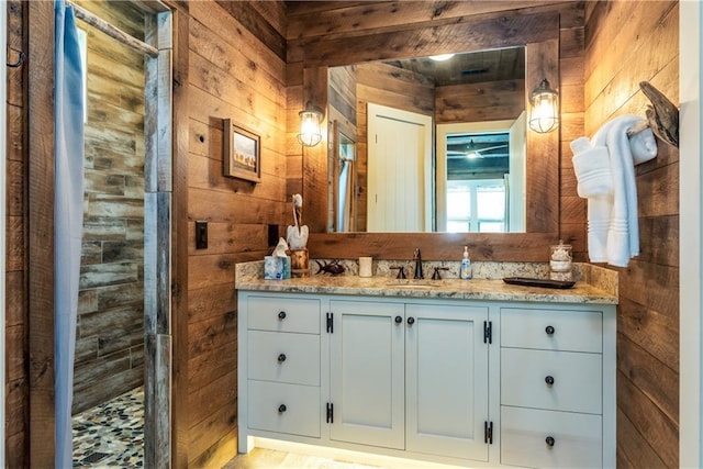 bathroom with wood walls, walk in shower, and vanity