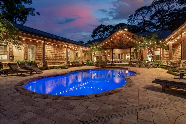 pool at dusk featuring a patio area