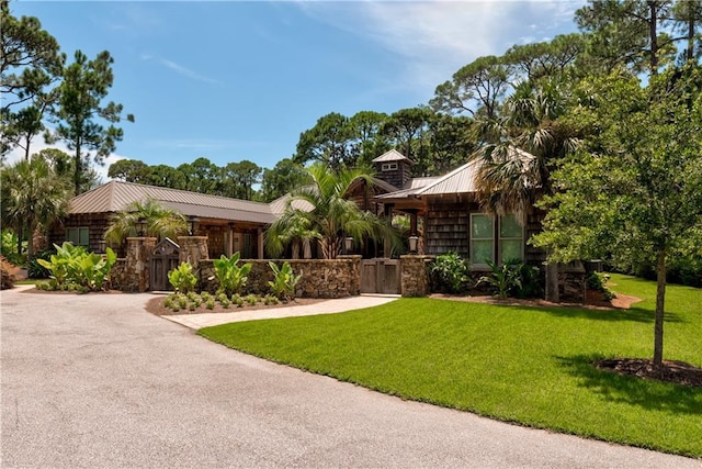 view of front facade with driveway, fence, metal roof, and a front yard