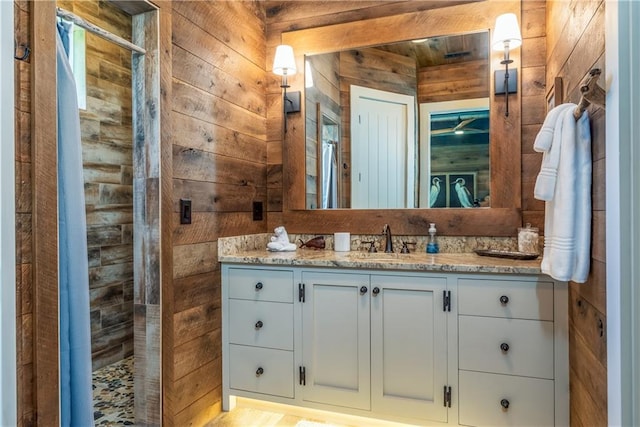 bathroom with vanity, wood walls, and a shower