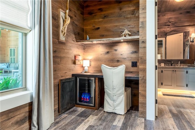 bar with wood-type flooring, wood walls, and white cabinets