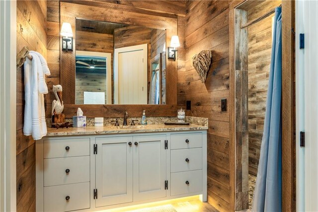 bathroom featuring vanity and wood walls