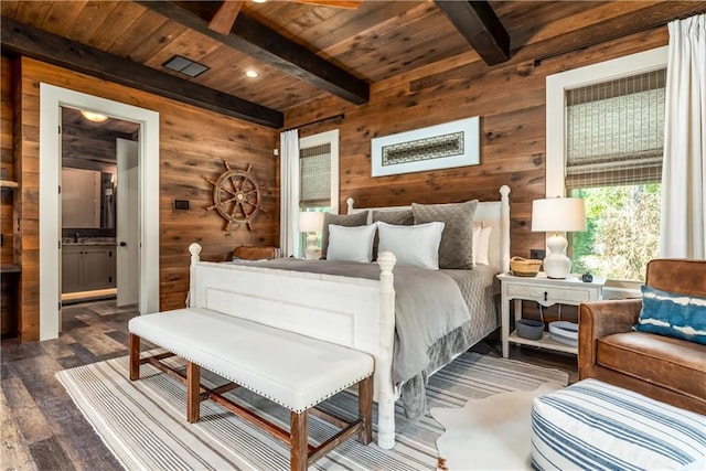 bedroom featuring wood walls, beamed ceiling, wooden ceiling, hardwood / wood-style floors, and ensuite bath