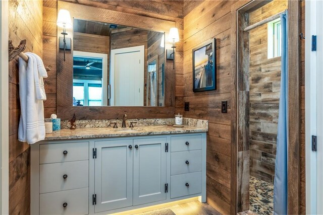 bathroom with vanity, hardwood / wood-style flooring, walk in shower, and wood walls