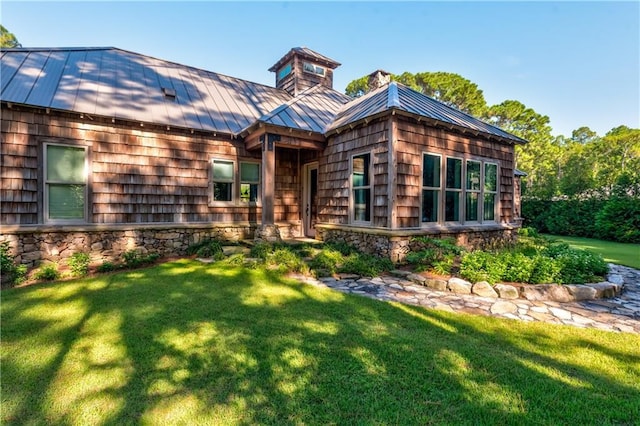 view of front of home with metal roof, a front lawn, a standing seam roof, and stone siding