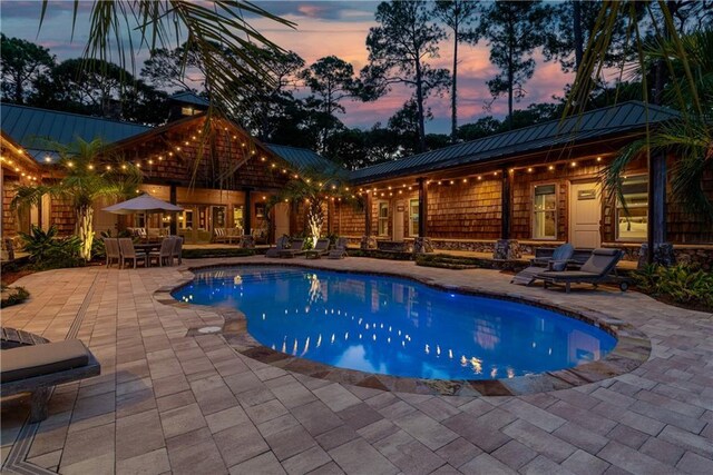 pool at dusk with a patio area