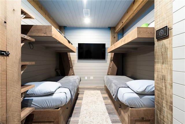 bedroom featuring wooden ceiling, visible vents, wooden walls, and wood finished floors