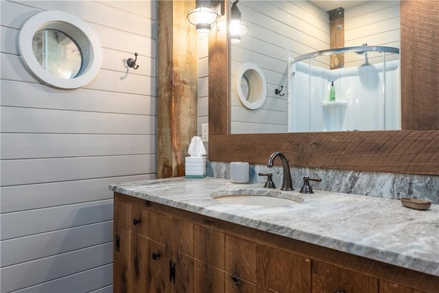 bathroom featuring vanity, wood walls, and a shower