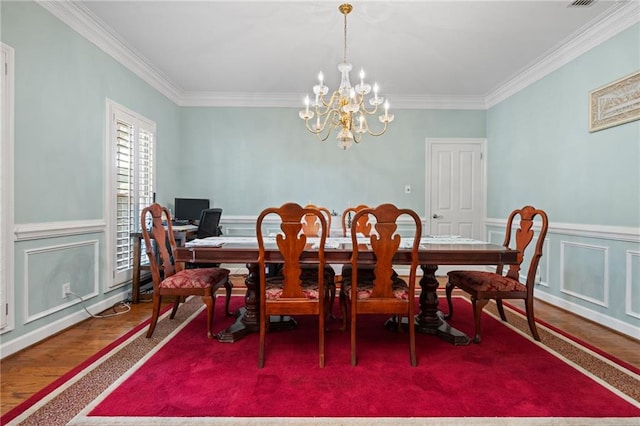 6905 Providence Estates Dr N, Mobile, AL 36695 - dining area with crown molding, a chandelier, wood finished floors, a wainscoted wall, and a decorative wall