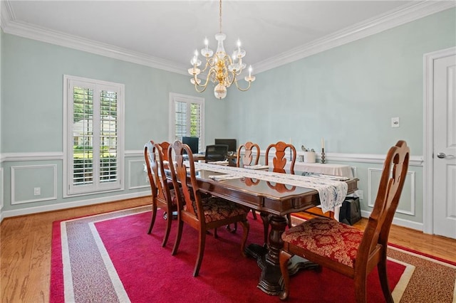 6905 Providence Estates Dr N, Mobile, AL 36695 - dining room featuring a chandelier, wood finished floors, crown molding, a wainscoted wall, and a decorative wall