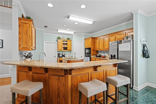 6905 Providence Estates Dr N, Mobile, AL 36695 - kitchen with black appliances, a peninsula, light stone counters, crown molding, and a kitchen breakfast bar