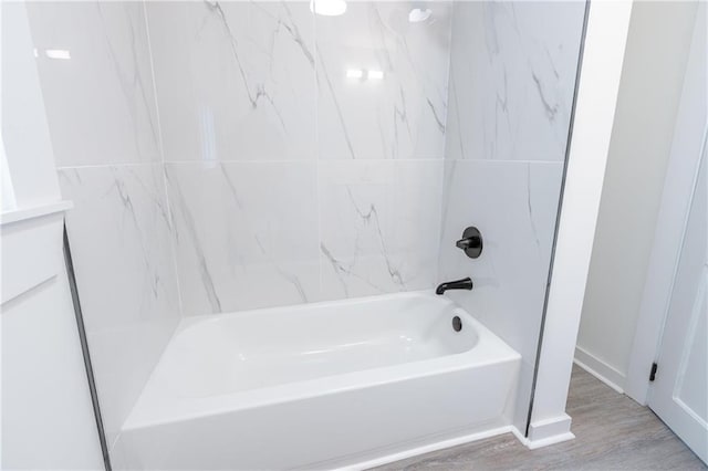 bathroom with hardwood / wood-style flooring and tiled shower / bath combo