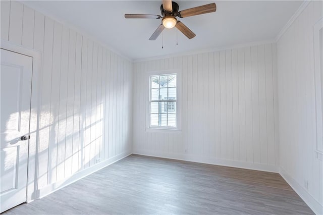 empty room featuring crown molding, wood-type flooring, and ceiling fan