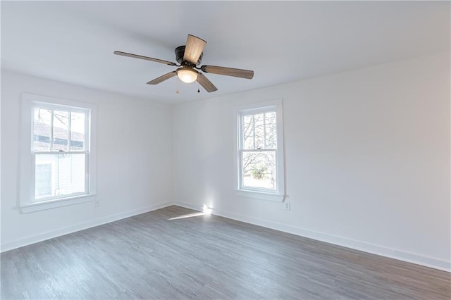 empty room featuring ceiling fan, a healthy amount of sunlight, and dark hardwood / wood-style flooring