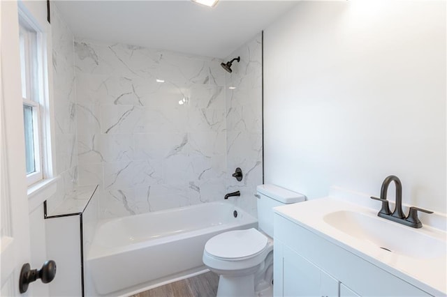 full bathroom featuring hardwood / wood-style floors, vanity, toilet, and tiled shower / bath