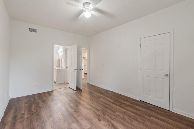 unfurnished bedroom with dark hardwood / wood-style flooring, ensuite bath, and ceiling fan