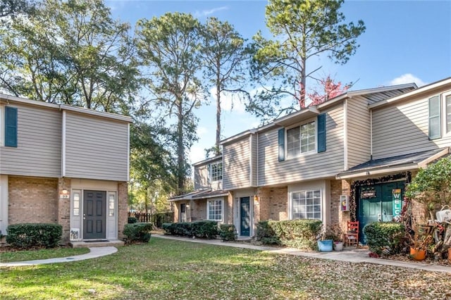 view of property featuring a front yard and brick siding