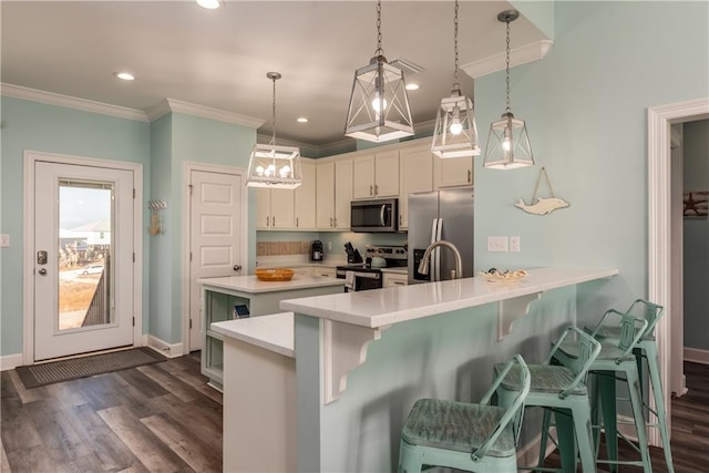 kitchen featuring appliances with stainless steel finishes, a breakfast bar, hanging light fixtures, a peninsula, and light countertops