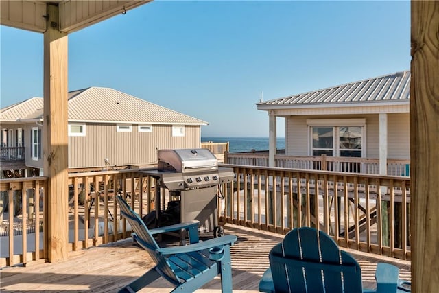 wooden terrace featuring a water view and a grill