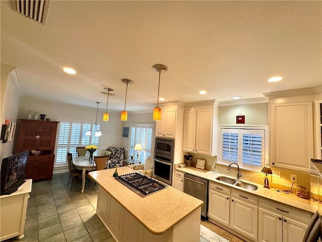 kitchen featuring a center island, sink, stainless steel appliances, pendant lighting, and white cabinets