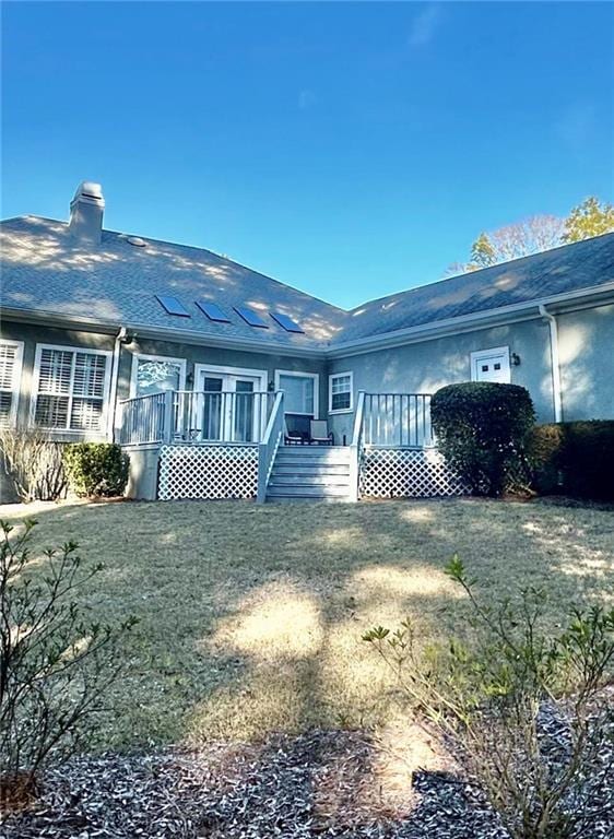 rear view of property featuring a deck and a lawn