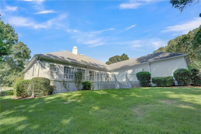 rear view of house with a lawn and a wooden deck