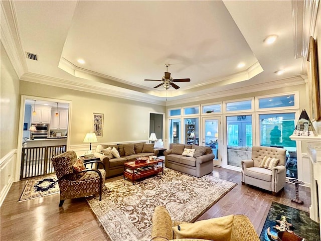 living room featuring hardwood / wood-style flooring, ceiling fan, a raised ceiling, and a premium fireplace