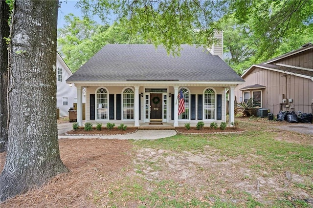 view of front of home featuring a porch, cooling unit, roof with shingles, and a chimney