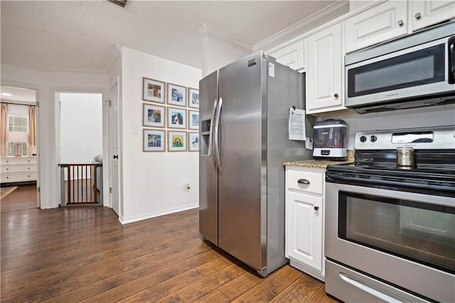 kitchen with a textured ceiling, white cabinets, stainless steel appliances, dark wood-style floors, and ornamental molding