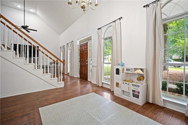 entrance foyer featuring stairway, ceiling fan with notable chandelier, wood-type flooring, and high vaulted ceiling