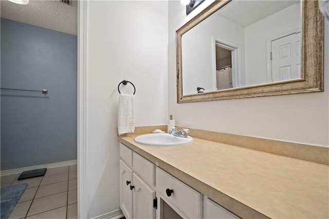 bathroom with tile patterned floors, a textured ceiling, vanity, and baseboards