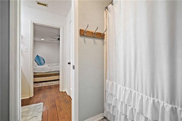 ensuite bathroom with a textured ceiling, connected bathroom, visible vents, baseboards, and wood finished floors