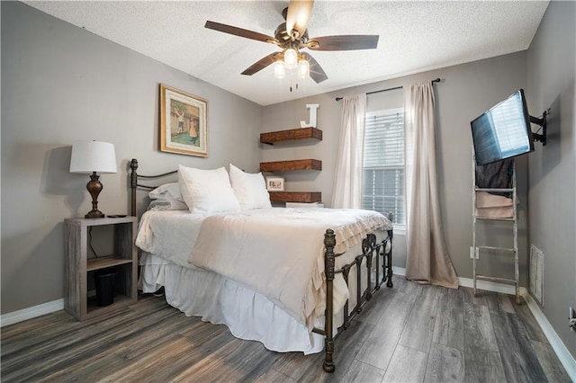 bedroom featuring baseboards, visible vents, wood finished floors, and a textured ceiling