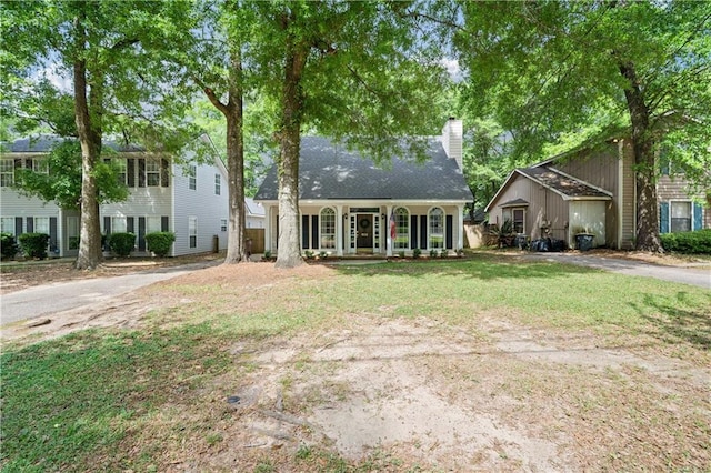 view of front of home with a front yard, a chimney, and a porch