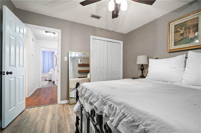 bedroom featuring a closet, a ceiling fan, visible vents, baseboards, and wood finished floors