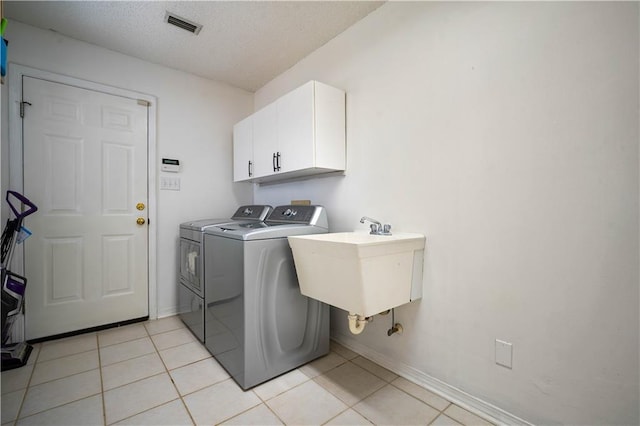 laundry room with light tile patterned floors, a textured ceiling, visible vents, washer and clothes dryer, and cabinet space