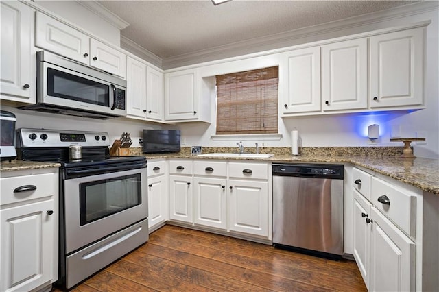 kitchen featuring white cabinetry, crown molding, a sink, stainless steel appliances, and dark wood-style floors