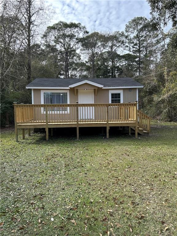 back of property with a wooden deck and a lawn