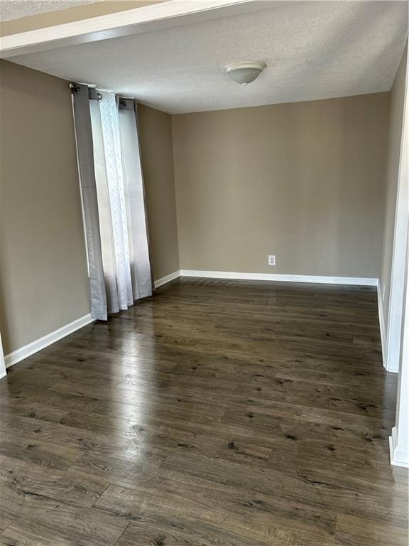 empty room featuring dark hardwood / wood-style flooring and a textured ceiling